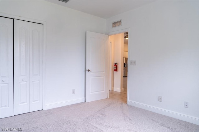 unfurnished bedroom with light colored carpet and a closet