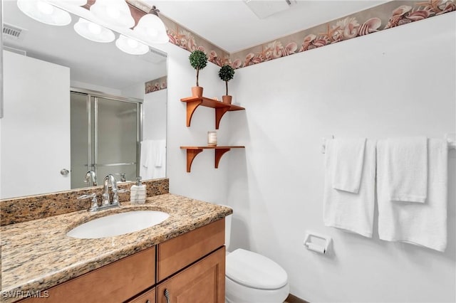 bathroom with vanity, a shower with shower door, and toilet