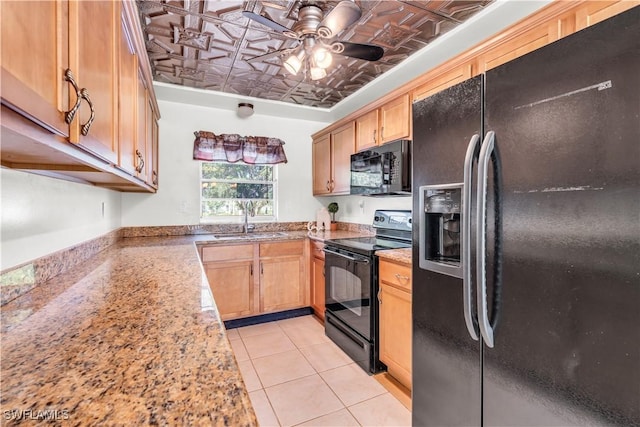 kitchen featuring light stone counters, ceiling fan, sink, black appliances, and light tile patterned floors