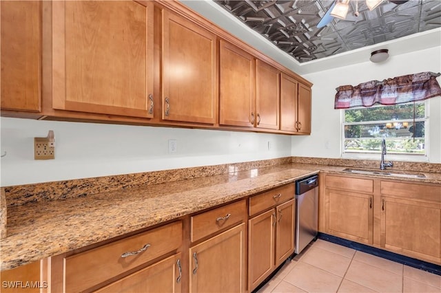 kitchen with stainless steel dishwasher, light tile patterned flooring, light stone countertops, and sink