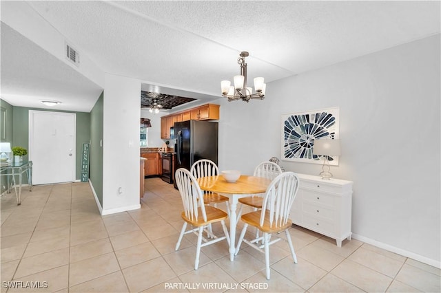 tiled dining room with ceiling fan with notable chandelier and a textured ceiling