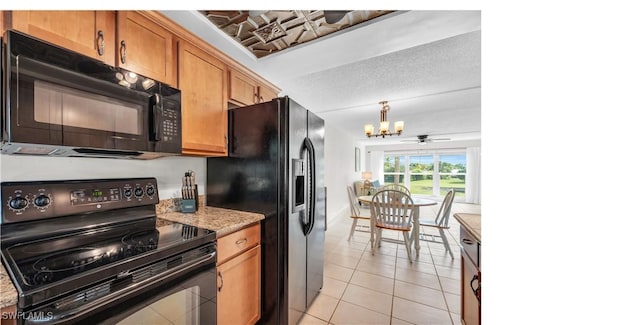 kitchen featuring black appliances, ceiling fan with notable chandelier, hanging light fixtures, light tile patterned floors, and light stone counters