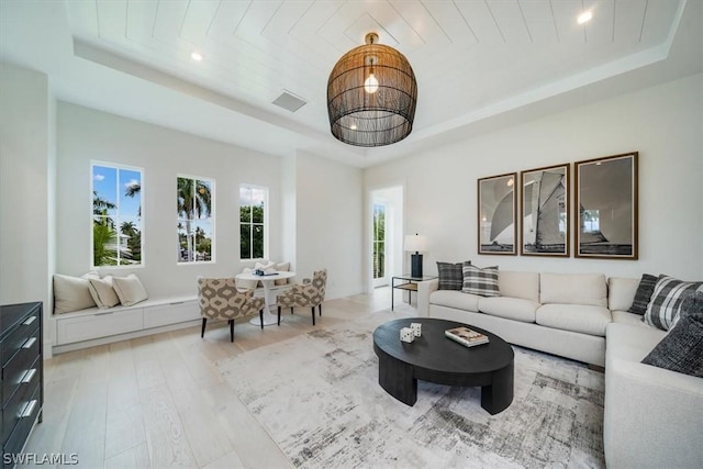 living room with light wood-type flooring, a tray ceiling, and wood ceiling