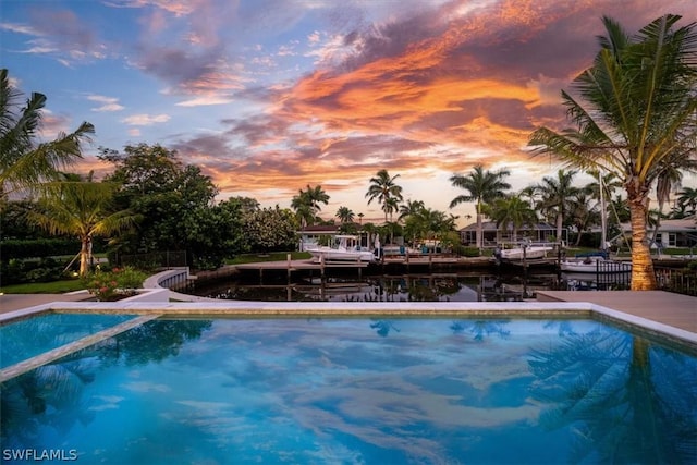 pool at dusk featuring a water view and a boat dock