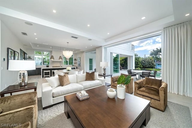 living room with a tray ceiling and an inviting chandelier