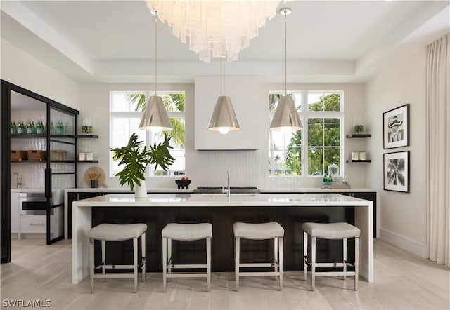 kitchen with a center island with sink, decorative light fixtures, a kitchen breakfast bar, and sink