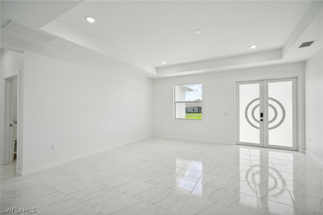 tiled empty room with a raised ceiling and french doors