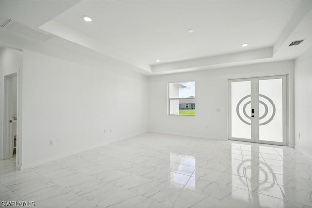 spare room with french doors and a tray ceiling