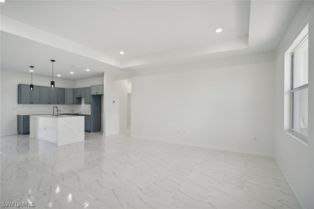 unfurnished living room with light tile patterned flooring, a raised ceiling, and sink