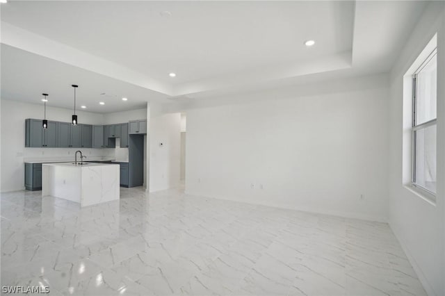 unfurnished living room featuring a raised ceiling and sink