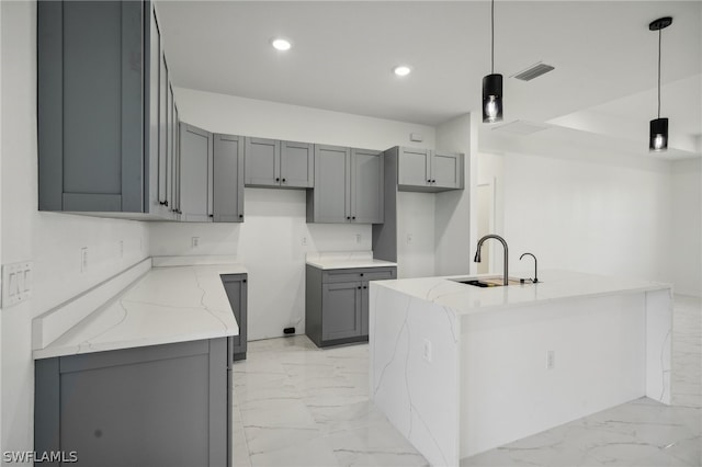 kitchen featuring gray cabinets, light tile patterned flooring, pendant lighting, sink, and a kitchen island with sink