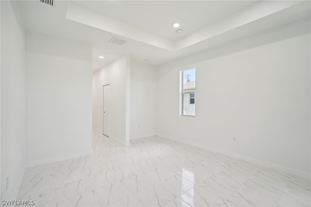 spare room featuring light tile patterned floors and a tray ceiling