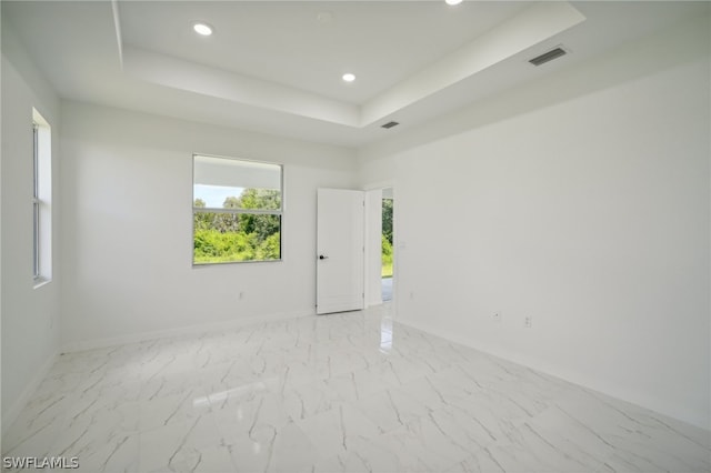 tiled spare room featuring a tray ceiling