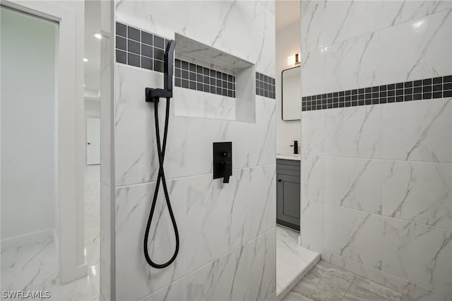 bathroom featuring tiled shower, vanity, tile patterned floors, and tile walls