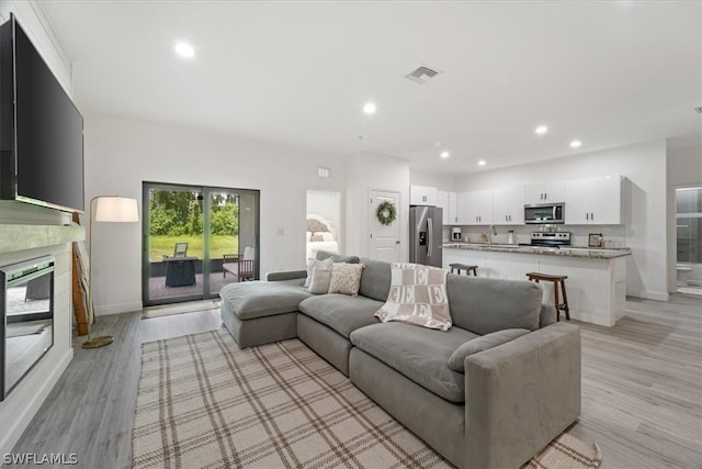 living room with light wood-type flooring, a fireplace, and sink