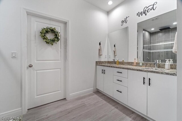 bathroom with a shower with shower door, hardwood / wood-style flooring, and vanity