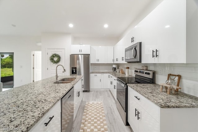 kitchen with light stone counters, sink, white cabinetry, and stainless steel appliances