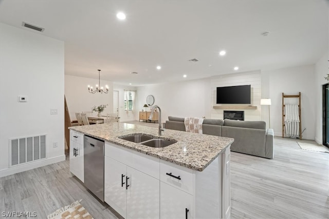 kitchen featuring white cabinetry, sink, light stone counters, stainless steel dishwasher, and a center island with sink