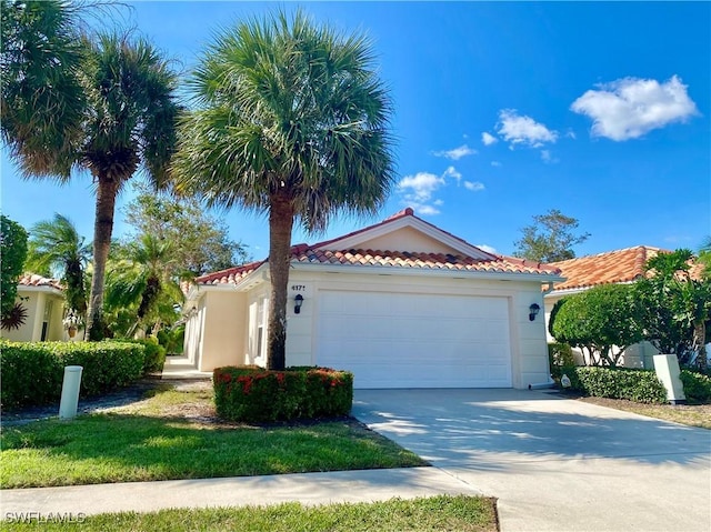 mediterranean / spanish-style house with driveway, an attached garage, a tiled roof, and stucco siding