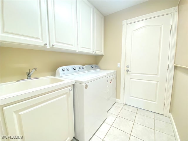 washroom featuring sink, washer and dryer, cabinets, and light tile patterned floors