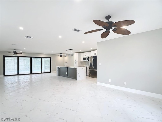 unfurnished living room featuring sink and ceiling fan