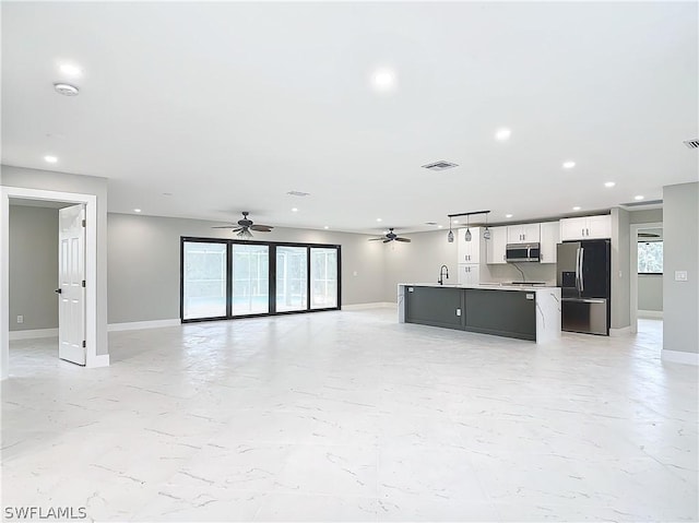 unfurnished living room featuring sink and ceiling fan