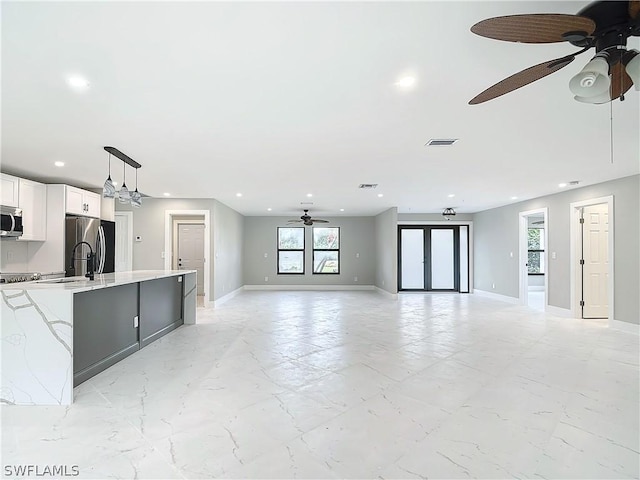 kitchen featuring decorative light fixtures, ceiling fan, stainless steel appliances, light stone countertops, and white cabinets