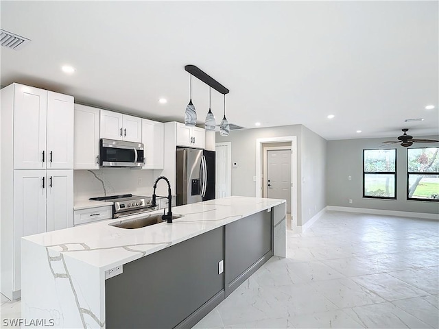 kitchen with white cabinetry, sink, stainless steel appliances, and an island with sink