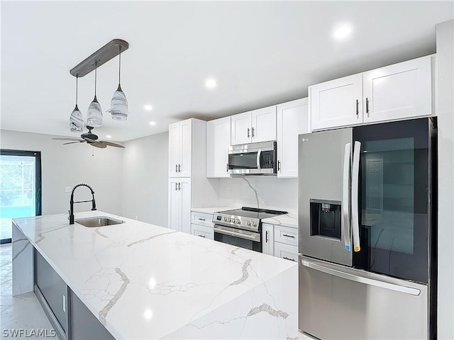 kitchen featuring sink, stainless steel appliances, light stone countertops, white cabinets, and decorative light fixtures