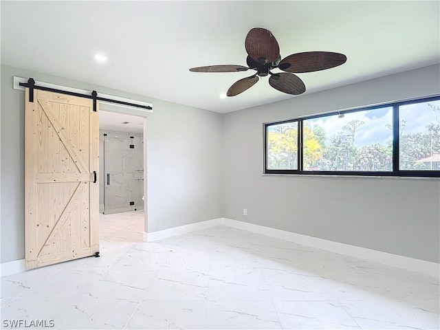 empty room featuring ceiling fan and a barn door