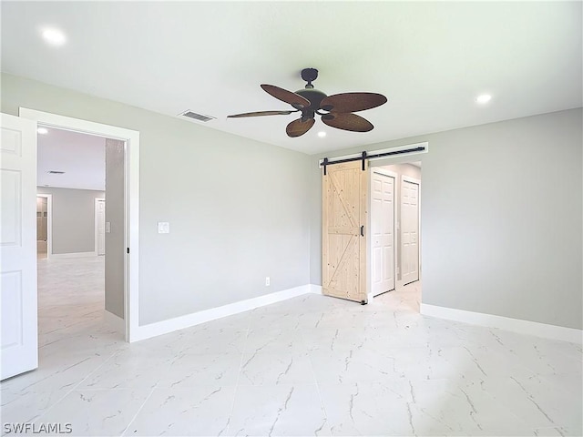 unfurnished bedroom featuring a barn door and ceiling fan