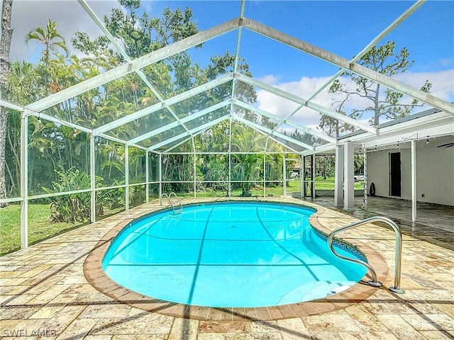 view of pool with glass enclosure and a patio area