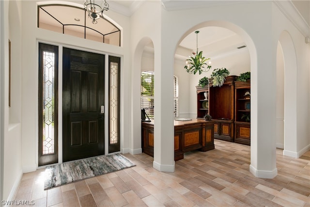 entrance foyer with ornamental molding and a chandelier