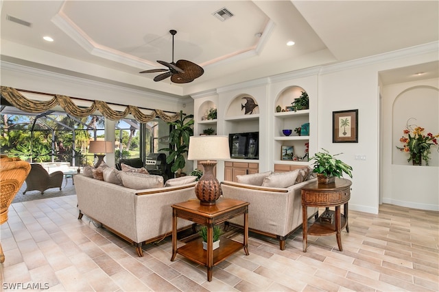 living room featuring ceiling fan, crown molding, built in features, and a raised ceiling