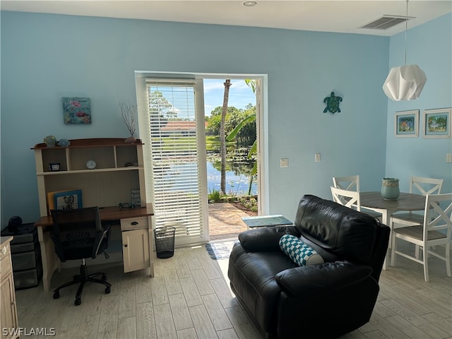 office with a water view and light hardwood / wood-style floors