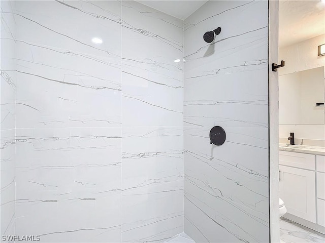 bathroom featuring vanity, toilet, and a tile shower