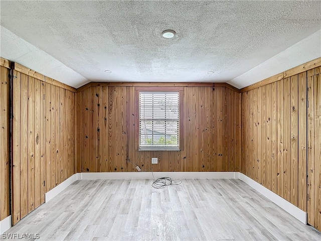 bonus room with hardwood / wood-style flooring, vaulted ceiling, and wooden walls