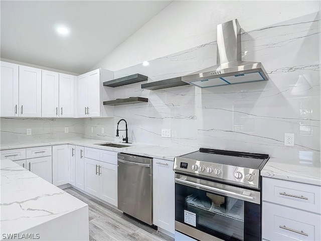 kitchen featuring lofted ceiling, sink, white cabinets, exhaust hood, and stainless steel appliances