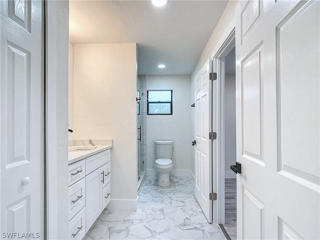 bathroom featuring vanity, a shower with shower door, and toilet