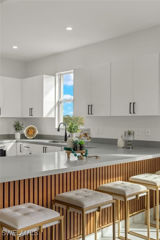 kitchen featuring a breakfast bar area, sink, and white cabinetry