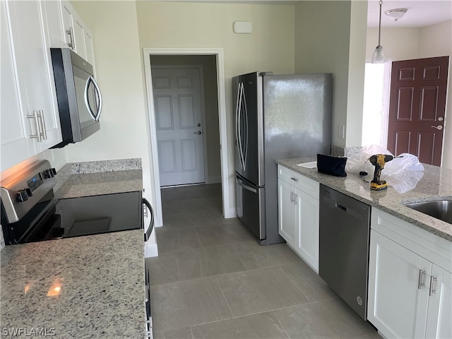 kitchen with stainless steel appliances, tile flooring, white cabinetry, and light stone counters