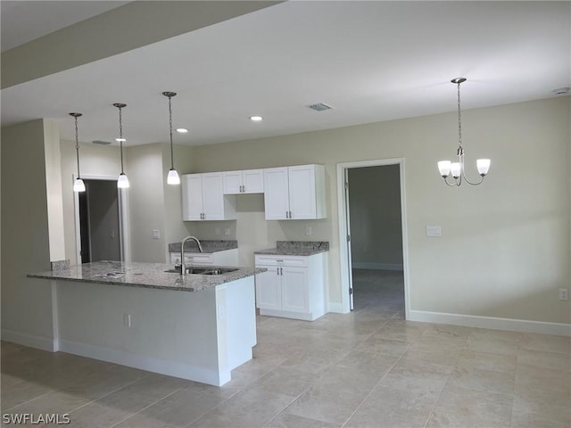 kitchen with sink, white cabinetry, decorative light fixtures, kitchen peninsula, and stone counters