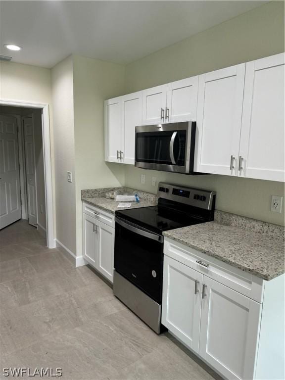 kitchen with light stone countertops, appliances with stainless steel finishes, and white cabinets