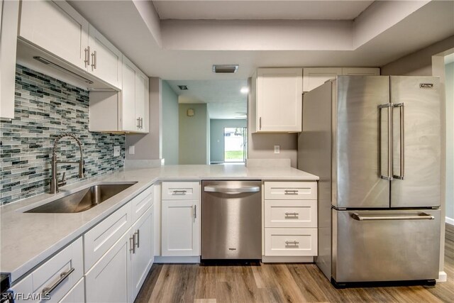 4508 Santa Barbara Blvd Unit 102, Cape Coral, FL 33914 - kitchen with stainless steel appliances, a sink, wood finished floors, white cabinets, and light countertops