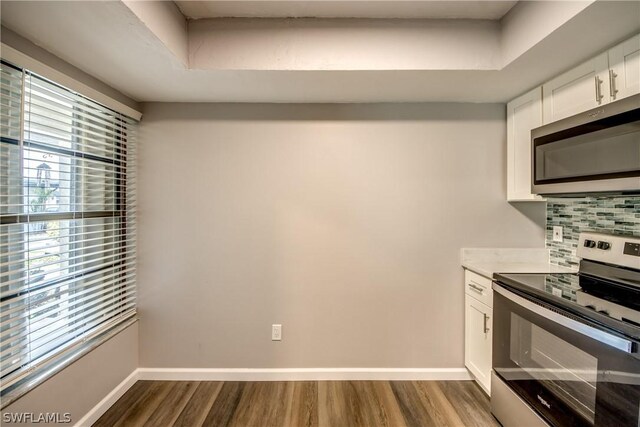 4508 Santa Barbara Blvd Unit 102, Cape Coral, FL 33914 - kitchen featuring appliances with stainless steel finishes, dark wood-type flooring, white cabinets, baseboards, and tasteful backsplash
