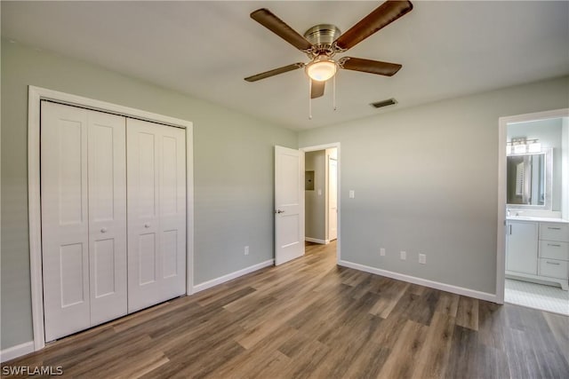 4508 Santa Barbara Blvd Unit 102, Cape Coral, FL 33914 - unfurnished bedroom with wood finished floors, a closet, baseboards, ensuite bath, and ceiling fan
