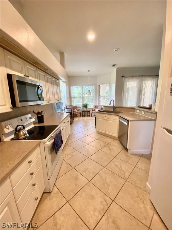 kitchen with light tile patterned floors, stainless steel appliances, hanging light fixtures, and sink