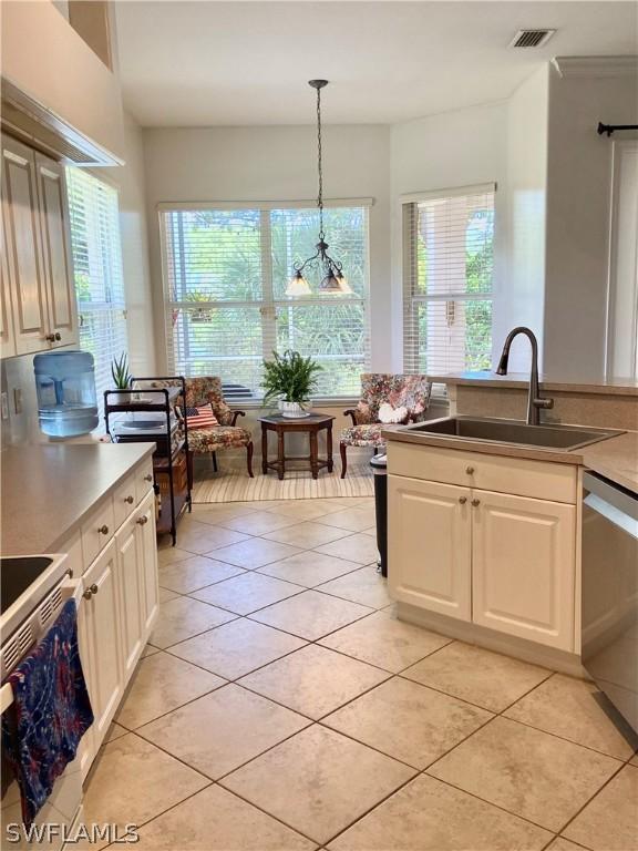 kitchen with white electric stove, visible vents, dishwasher, decorative light fixtures, and a sink