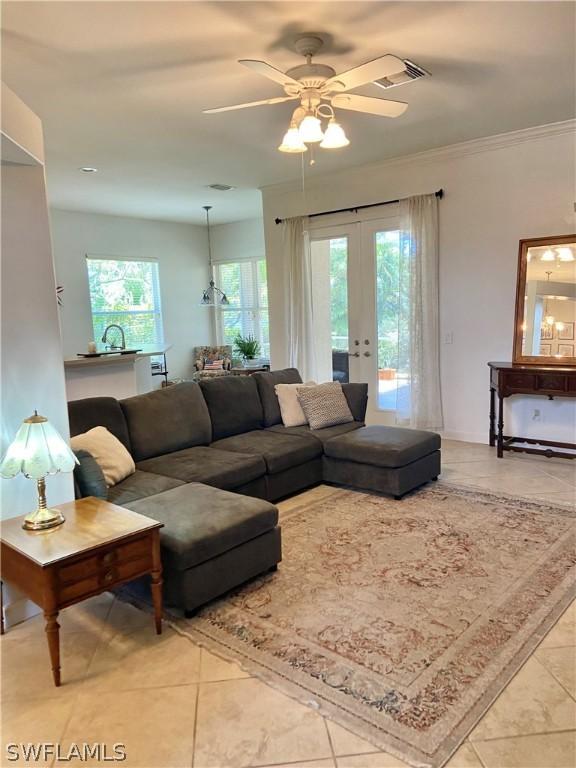 living area featuring visible vents, a ceiling fan, ornamental molding, french doors, and light tile patterned flooring