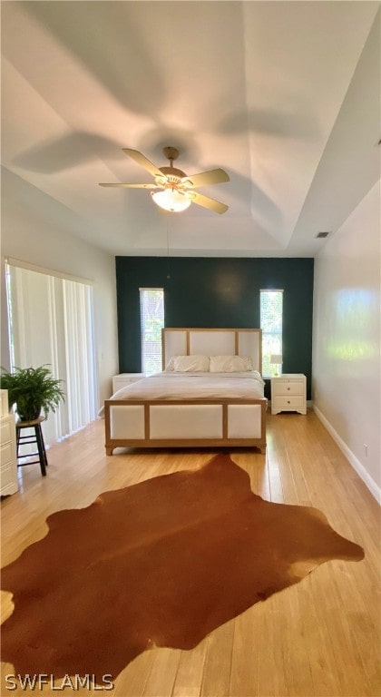 unfurnished bedroom featuring a tray ceiling, light hardwood / wood-style floors, and ceiling fan